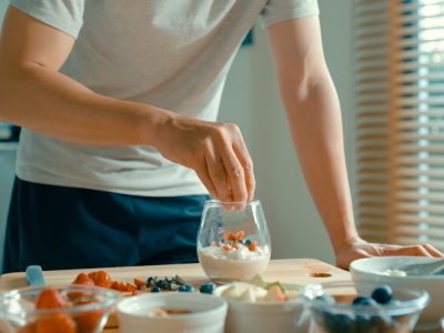 Closeup of young Asian man preparing yogurt and muesli breakfast at modern home. Diet and healthy food morning routine. Closeup of young Asian man preparing yogurt and muesli breakfast at modern home. Diet and healthy food morning routine concept.
